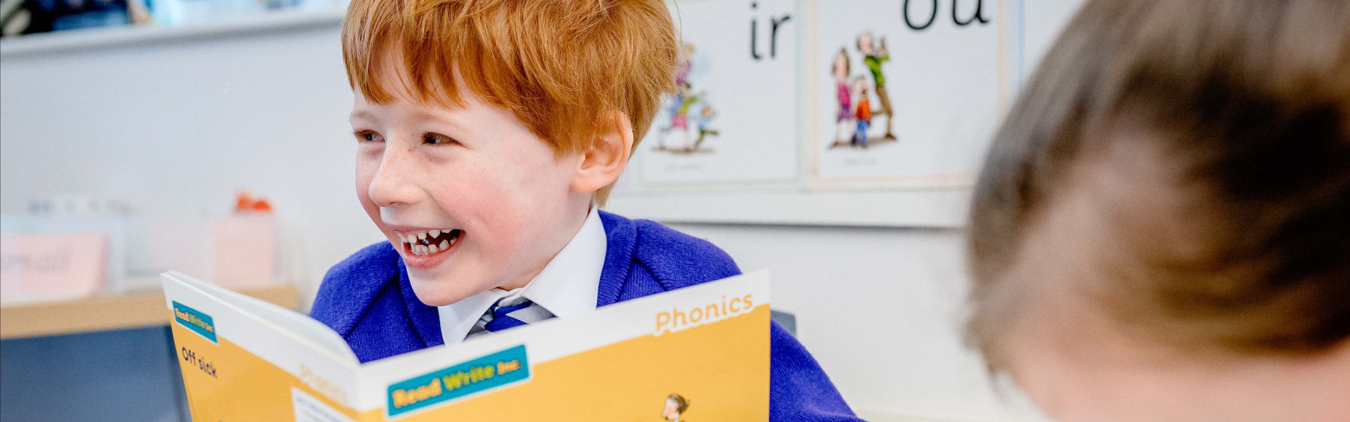 Child reading Phonics book and smiling